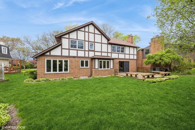 6483 Indianhead Trl, Indian Head Park, IL 60525 - rear view of house featuring brick siding, a chimney, a lawn, and stucco siding