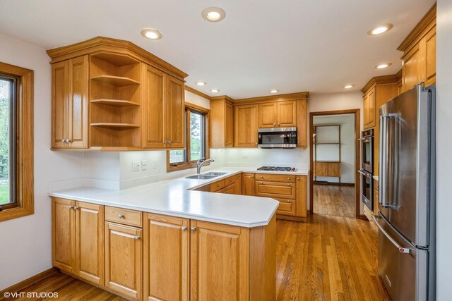 6483 Indianhead Trl, Indian Head Park, IL 60525 - kitchen with stainless steel appliances, a sink, a peninsula, dark wood-style flooring, and light countertops