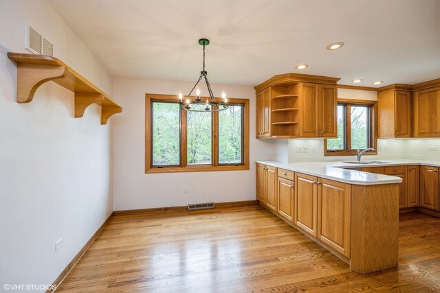 6483 Indianhead Trl, Indian Head Park, IL 60525 - kitchen featuring open shelves, a sink, a chandelier, a peninsula, and light wood-style flooring