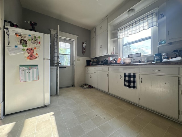 1309 S Main St, Bloomington, IL 61701 - kitchen with freestanding refrigerator, open shelves, white cabinets, and light tile patterned flooring