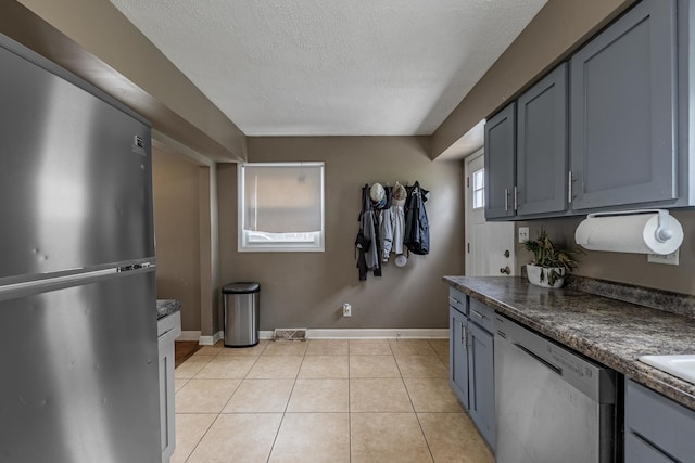 205 Glen St, West Chicago, IL 60185 - kitchen featuring appliances with stainless steel finishes, a textured ceiling, dark countertops, light tile patterned floors, and baseboards