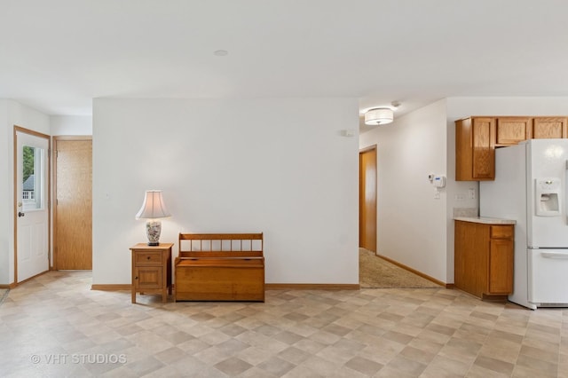 5203 Brighton Ln, Plainfield, IL 60586 - kitchen featuring white fridge with ice dispenser, baseboards, light countertops, and brown cabinetry
