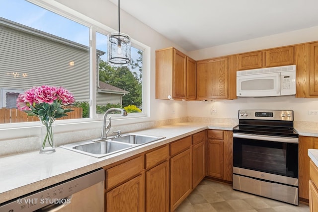 5203 Brighton Ln, Plainfield, IL 60586 - kitchen featuring appliances with stainless steel finishes, a sink, light countertops, hanging light fixtures, and brown cabinetry
