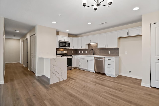 2034 W 75th Pl Unit 32, Merrillville, IN 46410 - kitchen featuring stainless steel appliances, light wood finished floors, white cabinetry, decorative backsplash, and recessed lighting