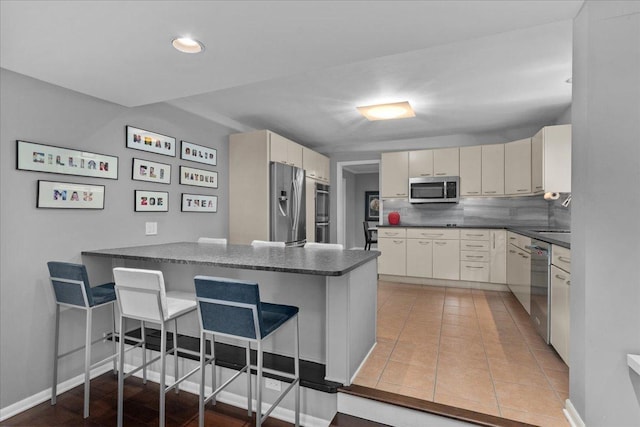185 Carlisle Ave, Deerfield, IL 60015 - kitchen featuring stainless steel appliances, a peninsula, dark countertops, a kitchen breakfast bar, and recessed lighting