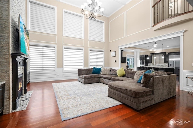 4748 Sassafras Ln, Naperville, IL 60564 - living area with ornamental molding, a decorative wall, a stone fireplace, a chandelier, and dark wood finished floors