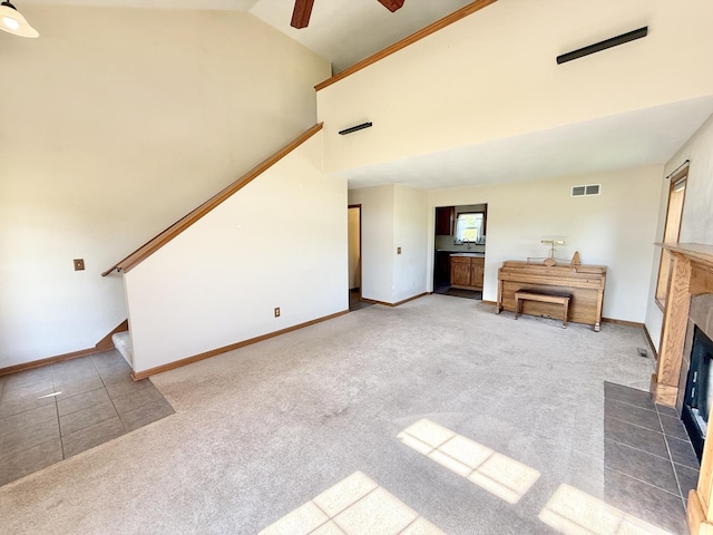 2123 Maxine Ln, Rockford, IL 61102 - unfurnished living room with stairway, ceiling fan, carpet floors, a tile fireplace, and high vaulted ceiling