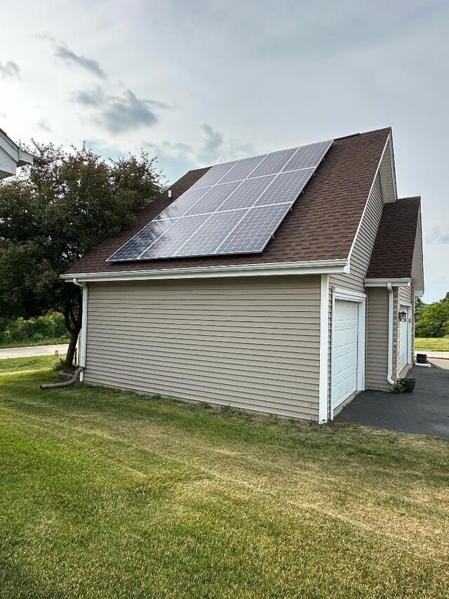 2123 Maxine Ln, Rockford, IL 61102 - view of property exterior with roof mounted solar panels, a yard, roof with shingles, and an attached garage
