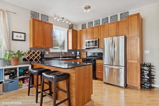 2215 W Augusta Blvd Unit 2E, Chicago, IL 60622 - kitchen with appliances with stainless steel finishes, a sink, light wood-style floors, a kitchen breakfast bar, and dark countertops