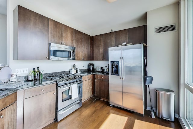 757 N Orleans St Unit 909, Chicago, IL 60654 - kitchen featuring stainless steel appliances, dark wood finished floors, dark stone countertops, and dark brown cabinetry