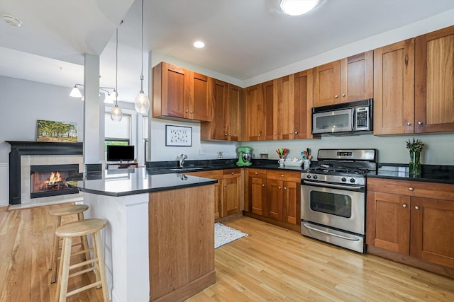 626 Judson Ave Unit 3, Evanston, IL 60202 - kitchen featuring stainless steel appliances, a sink, dark countertops, light wood-style flooring, and a breakfast bar area