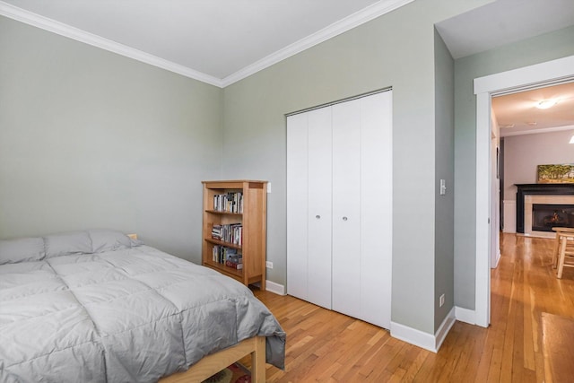 626 Judson Ave Unit 3, Evanston, IL 60202 - bedroom featuring crown molding, light wood-style floors, a closet, a fireplace, and baseboards
