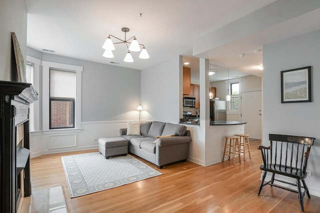 626 Judson Ave Unit 3, Evanston, IL 60202 - living area featuring light wood-type flooring, a fireplace, a chandelier, and a wainscoted wall