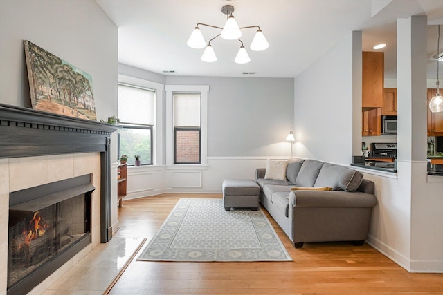 626 Judson Ave Unit 3, Evanston, IL 60202 - living room with light wood-style floors, a tiled fireplace, a wainscoted wall, and a chandelier