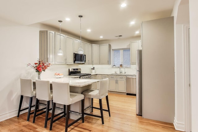 5319 W Cullom Ave, Chicago, IL 60641 - kitchen featuring stainless steel appliances, a peninsula, a breakfast bar, a sink, and light stone countertops