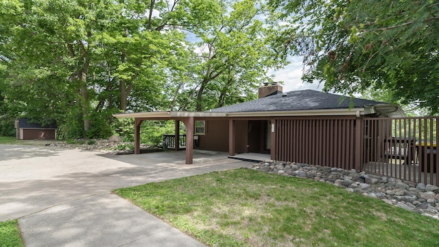 605 N 4th St, Oregon, IL 61061 - back of house featuring a chimney, concrete driveway, roof with shingles, and a carport