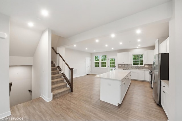 790 Weller Dr, Des Plaines, IL 60016 - kitchen with freestanding refrigerator, a kitchen island, light countertops, tasteful backsplash, and light wood finished floors