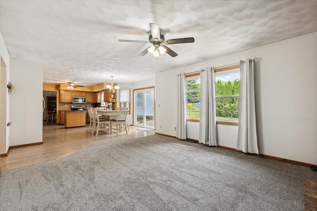 307 Shelden Dr, Winnebago, IL 61088 - living room featuring a ceiling fan, a chandelier, baseboards, and light colored carpet