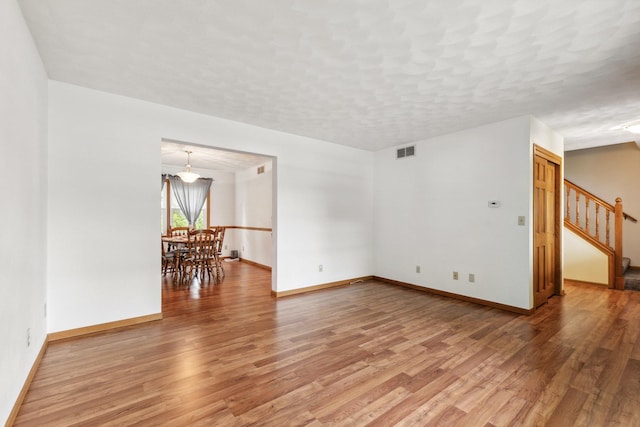 307 Shelden Dr, Winnebago, IL 61088 - unfurnished room featuring light wood-style flooring, stairway, baseboards, and a textured ceiling