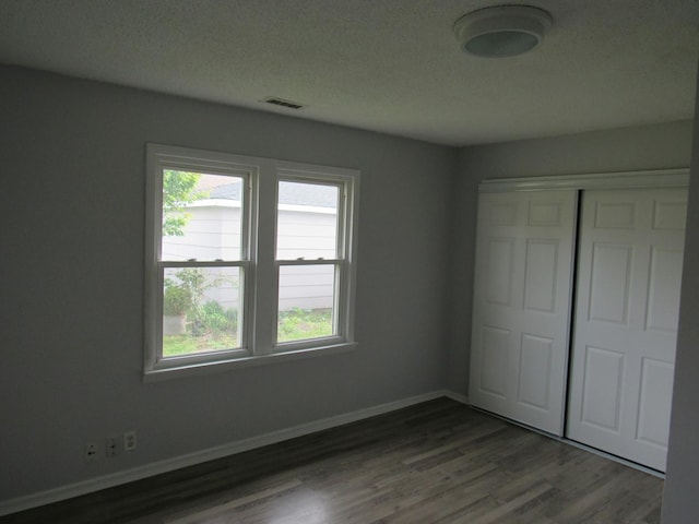 1503 Cherokee Dr, Round Lake Beach, IL 60073 - unfurnished bedroom featuring multiple windows, wood finished floors, a closet, baseboards, and a textured ceiling