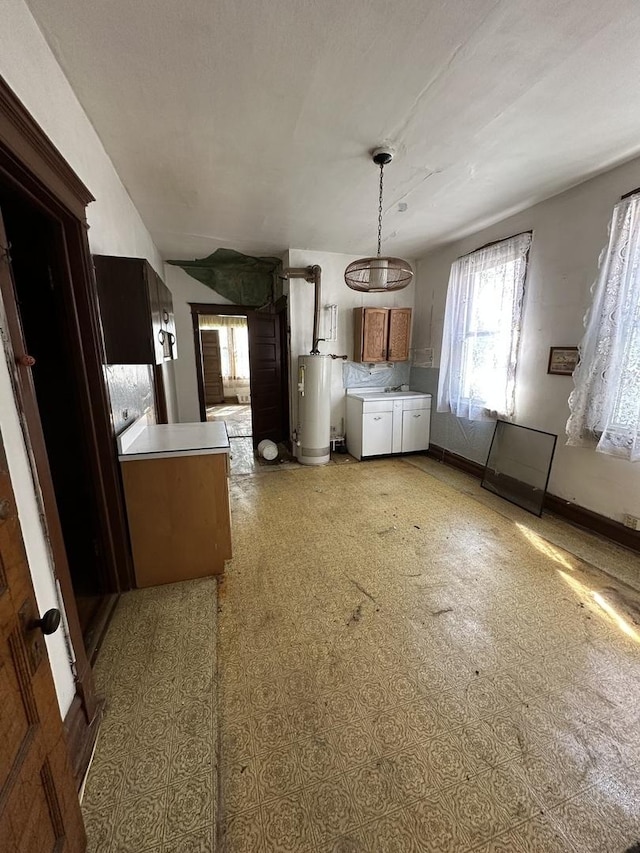 4636 S Wolcott Ave, Chicago, IL 60609 - kitchen featuring gas water heater, baseboards, pendant lighting, brown cabinetry, and light countertops