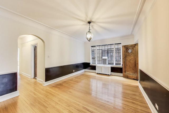 7350 N Ridge Blvd Unit 21B, Chicago, IL 60645 - spare room with radiator, wood finished floors, arched walkways, crown molding, and baseboards