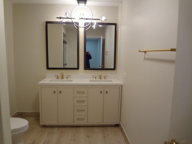 1108 Castilian Ct Unit 121, Glenview, IL 60025 - bathroom with a chandelier, wood finished floors, toilet, double vanity, and baseboards