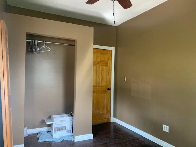 122 Portland Ave, Oglesby, IL 61348 - unfurnished bedroom with baseboards, dark wood-style flooring, and a ceiling fan
