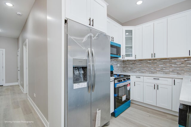 3926 W Arthington St, Chicago, IL 60624 - kitchen with stainless steel fridge, gas range oven, light wood-type flooring, decorative backsplash, and white cabinets