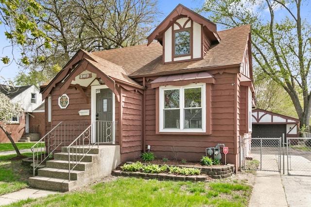 3413 N Schultz Dr, Lansing, IL 60438 - tudor house featuring a gate, a shingled roof, an outbuilding, and a garage