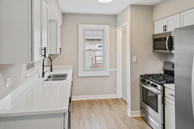 3413 N Schultz Dr, Lansing, IL 60438 - kitchen featuring appliances with stainless steel finishes, a sink, light wood-type flooring, white cabinets, and baseboards