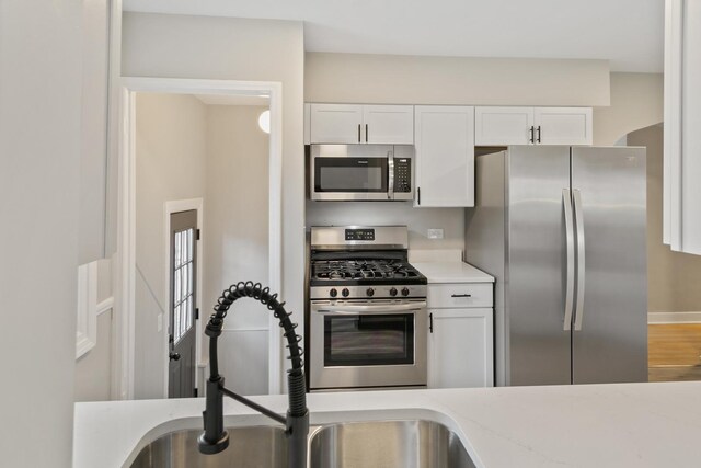 3413 N Schultz Dr, Lansing, IL 60438 - kitchen with stainless steel appliances, a sink, white cabinets, and wood finished floors