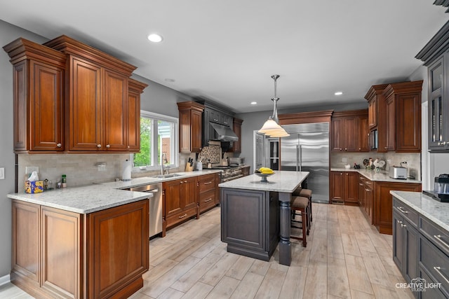 1900 Millburne Rd, Lake Forest, IL 60045 - kitchen with high quality appliances, decorative backsplash, light stone countertops, under cabinet range hood, and light wood-style floors