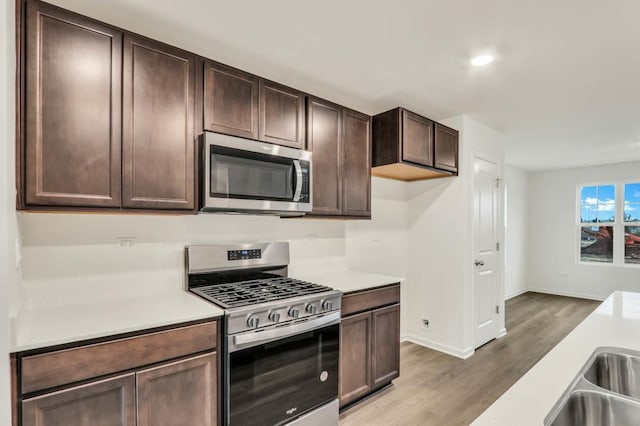358 Bridgeview Ct, Saint Charles, IL 60174 - kitchen featuring appliances with stainless steel finishes, light countertops, wood finished floors, dark brown cabinetry, and baseboards
