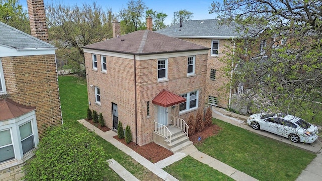 9632 S Yale Ave, Chicago, IL 60628 - view of home's exterior featuring roof with shingles, brick siding, a lawn, and a chimney