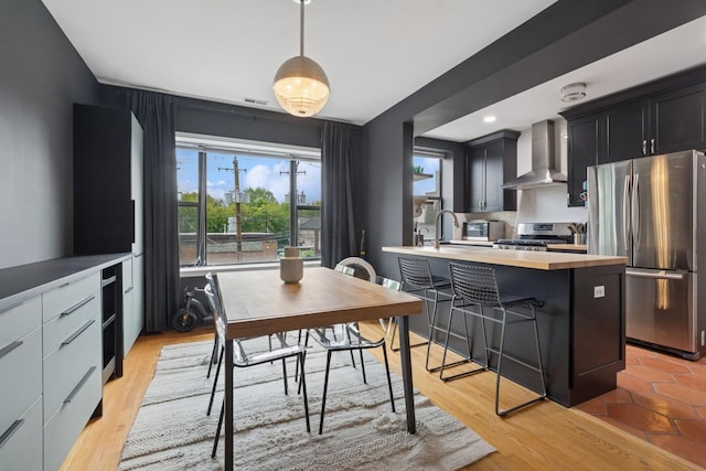 5730 N Hermitage Ave Unit 2, Chicago, IL 60660 - kitchen with stainless steel appliances, wall chimney exhaust hood, plenty of natural light, and a breakfast bar area