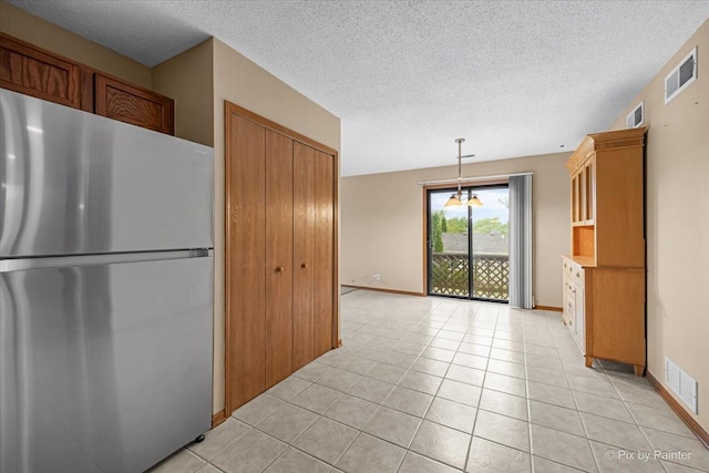 11405 Douglas Ave Unit D, Huntley, IL 60142 - kitchen featuring freestanding refrigerator, a textured ceiling, light tile patterned floors, baseboards, and brown cabinets