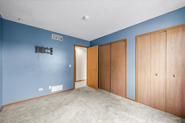 11405 Douglas Ave Unit D, Huntley, IL 60142 - unfurnished bedroom featuring two closets, carpet floors, baseboards, and a textured ceiling