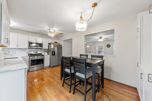1191 Narragansett Dr, Carol Stream, IL 60188 - kitchen with appliances with stainless steel finishes, a ceiling fan, a sink, white cabinetry, and light wood-style floors
