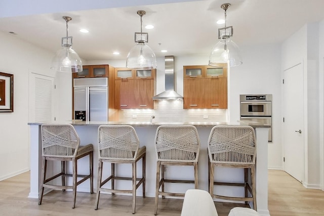 500 W Superior St Unit 612, Chicago, IL 60654 - kitchen featuring built in refrigerator, wall chimney range hood, brown cabinets, tasteful backsplash, and recessed lighting