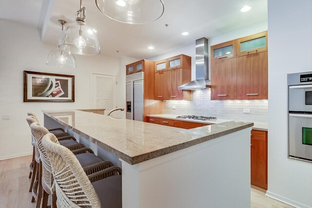 500 W Superior St Unit 612, Chicago, IL 60654 - kitchen with wall chimney range hood, stainless steel appliances, a kitchen island, a breakfast bar area, and tasteful backsplash