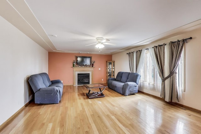 1347 Rainbow Cir, Manteno, IL 60950 - living room featuring a fireplace with flush hearth, light wood finished floors, ceiling fan, and baseboards