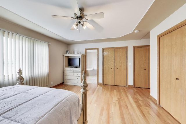 1347 Rainbow Cir, Manteno, IL 60950 - bedroom featuring light wood-style flooring, baseboards, ensuite bathroom, ceiling fan, and two closets