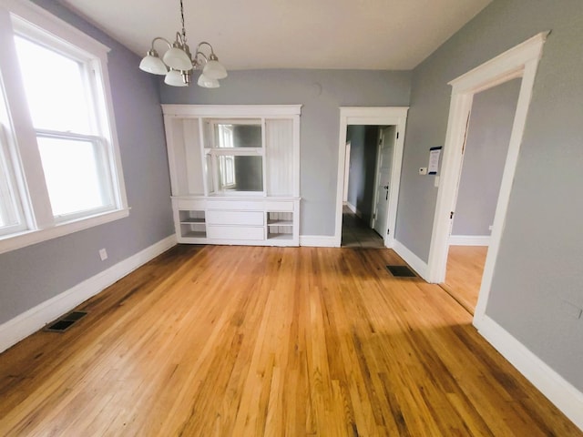 6801 S Oakley Ave, Chicago, IL 60636 - unfurnished dining area featuring a chandelier, light wood-style flooring, and baseboards