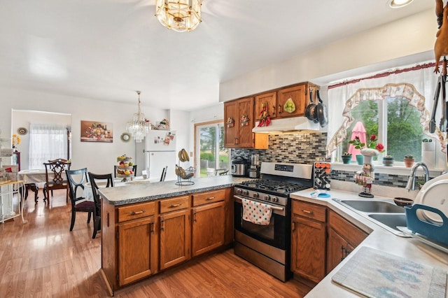 21705 W Knollwood Ct, Plainfield, IL 60544 - kitchen with stainless steel range with gas stovetop, freestanding refrigerator, a chandelier, a peninsula, and brown cabinets