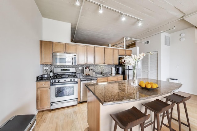 1525 S Sangamon St Unit 312, Chicago, IL 60608 - kitchen with appliances with stainless steel finishes, track lighting, light wood-style floors, a breakfast bar area, and decorative backsplash