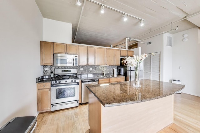 1525 S Sangamon St Unit 312, Chicago, IL 60608 - kitchen with stainless steel appliances, track lighting, dark stone countertops, light wood finished floors, and tasteful backsplash