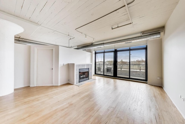 1525 S Sangamon St Unit 312, Chicago, IL 60608 - unfurnished living room featuring wood finished floors, a tiled fireplace, and a wall of windows