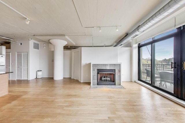 1525 S Sangamon St Unit 312, Chicago, IL 60608 - unfurnished living room featuring light wood-type flooring, a tiled fireplace, and track lighting