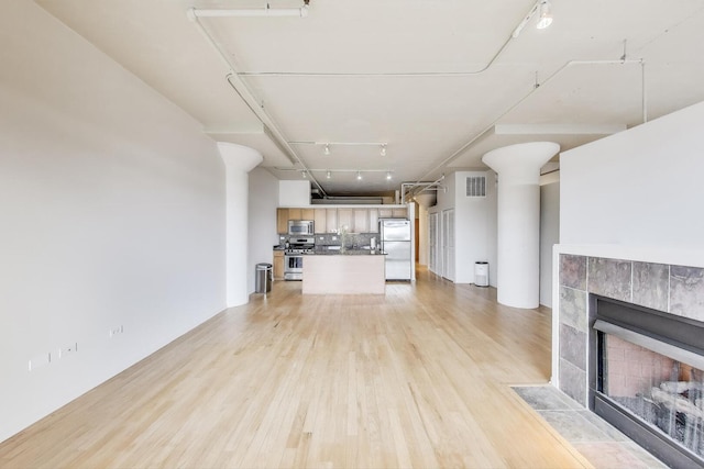 1525 S Sangamon St Unit 312, Chicago, IL 60608 - unfurnished living room featuring light wood-style flooring, rail lighting, and a tiled fireplace